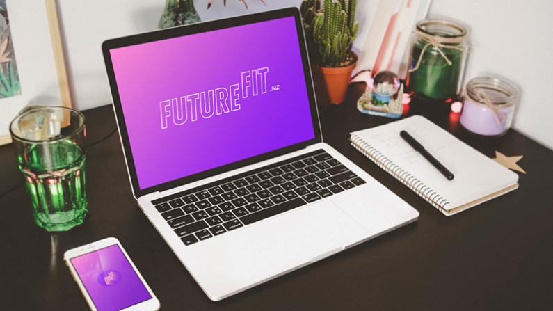 A laptop on a desk showing the logo of FutureFit.