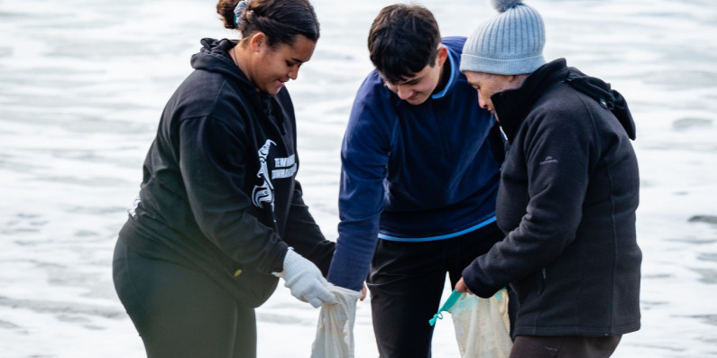 Three people picking up rubbish on East Cape Beach.