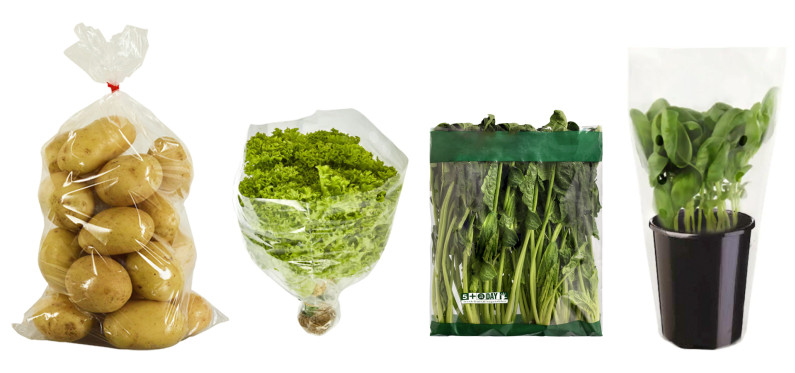 A line up of pre-packaged produce in single use bags. There are potatoes in a plastic bag, lettuce and spinach in bags, and herbs in a plastic sleeve.