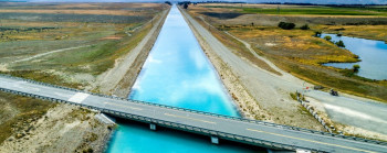 A straight, man-made river with a road-bridge across it.