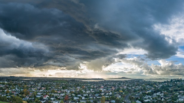 Dark grey clouds above a wide landscape of houses and trees.