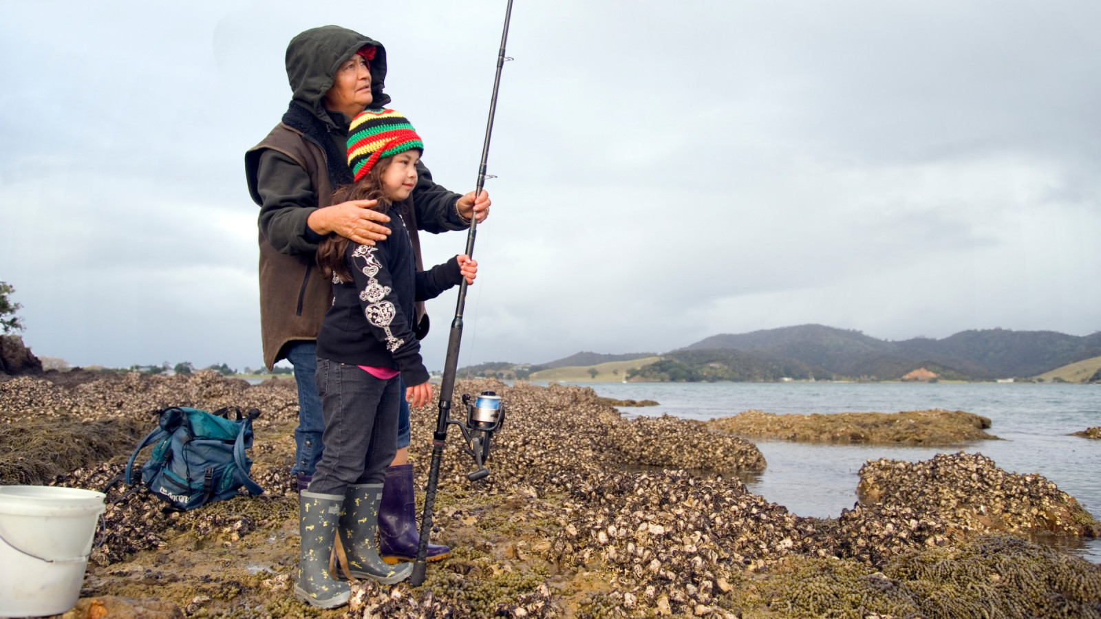 An older person and a young child fishing together in Whangaruru, Northland.