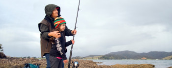 An older person and a young child fishing together in Whangaruru, Northland.
