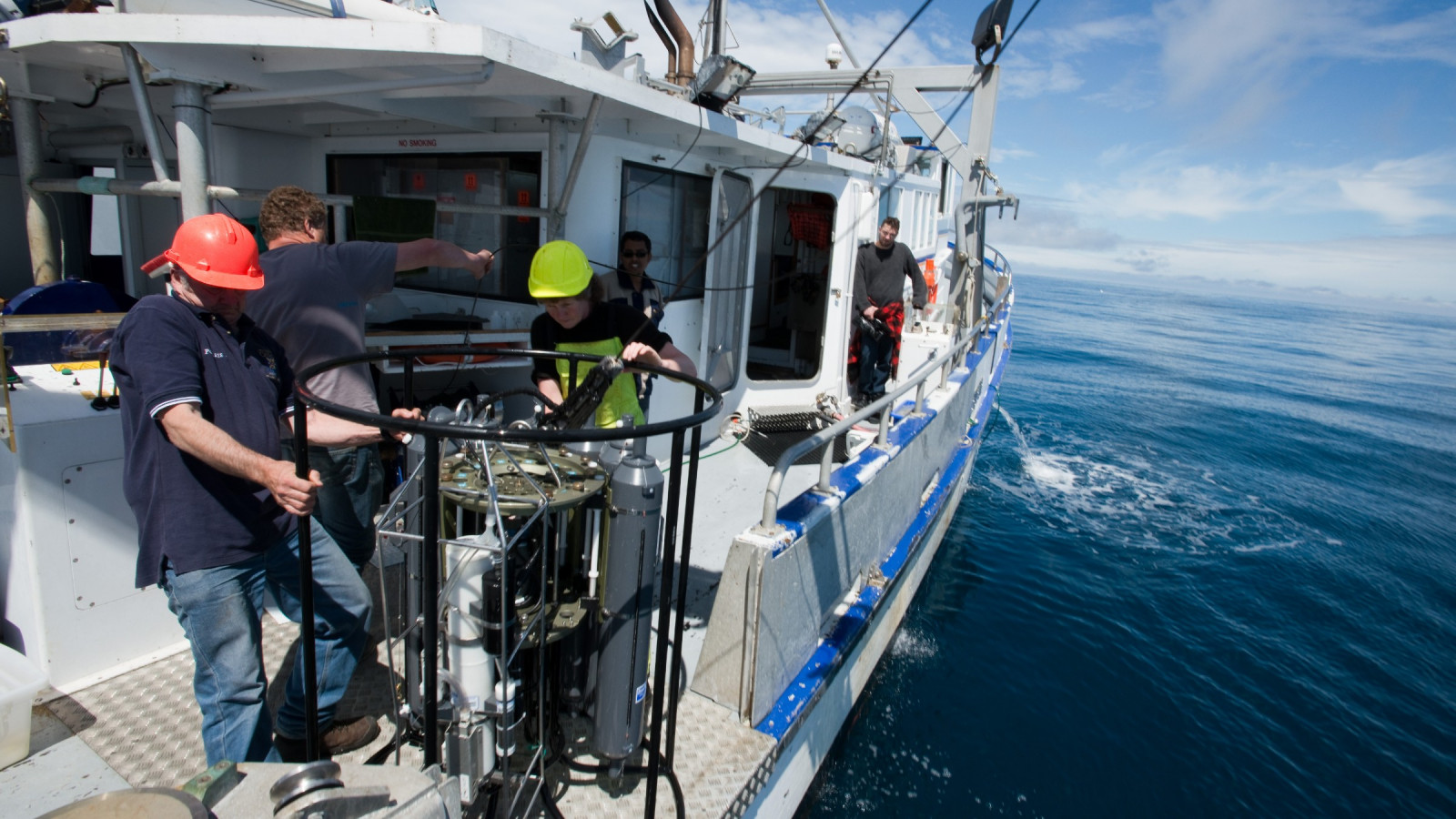 Crew on a boat at sea, collecting samples for ocean acidification studies.