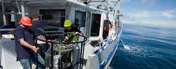 Crew on a boat at sea, collecting samples for ocean acidification studies.
