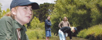 A group of young people standing in a river and testing the water.