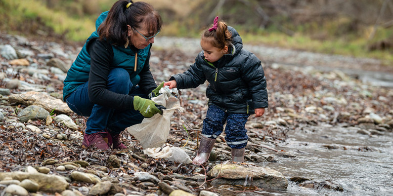 A woman and child picking up rubbish beside Clyde river Alexandra