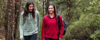 Two teenage girls walking on a track in a native forest.