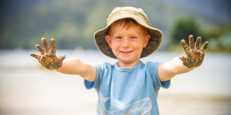 Boy with holding his hands up with sand on in Queen Charlotte Sounds, Marlborough