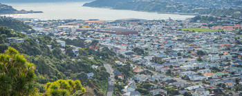 An aerial photo of Wellington showing hills, houses, a harbour and green hills.