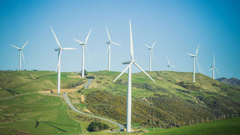 Nine wind turbines in a hilly landscape in Mākara, Wellington. 