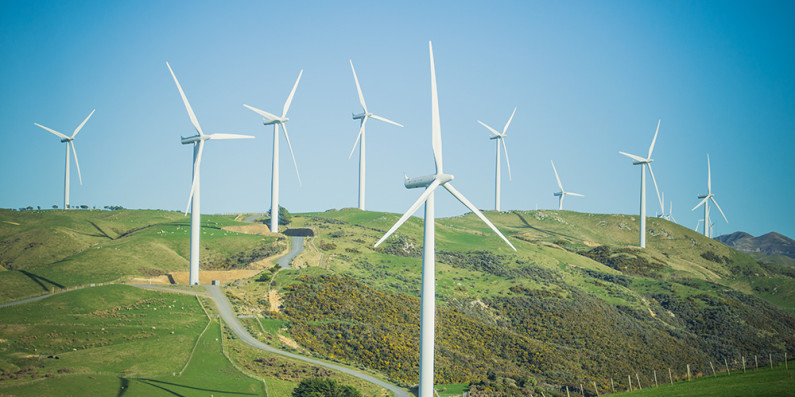 Nine wind turbines in a hilly landscape in Mākara, Wellington. 