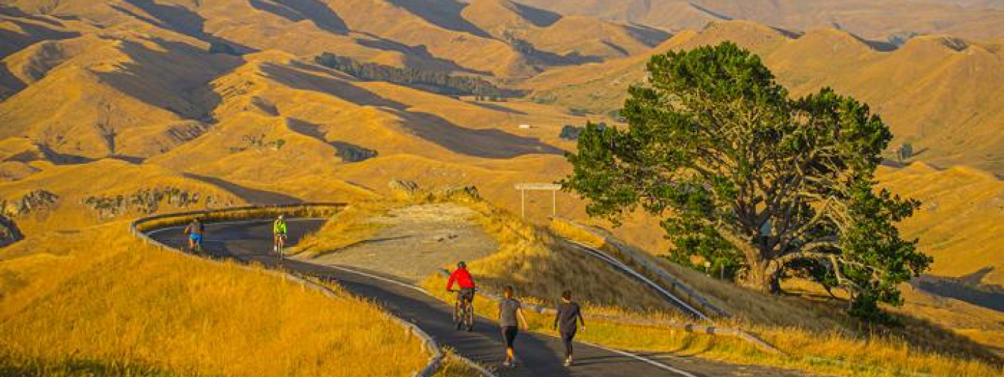 hills in the background with people walking and cycling up a road