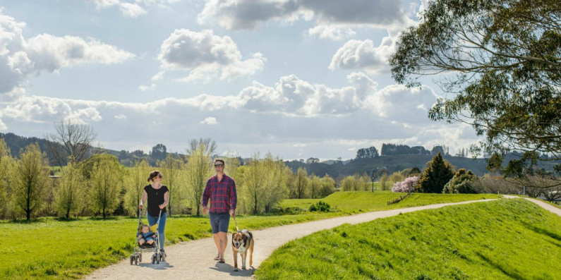 Two people walking on a path with a dog