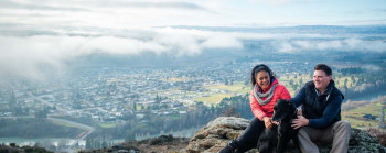 Two people sitting on a rock overlooking a town