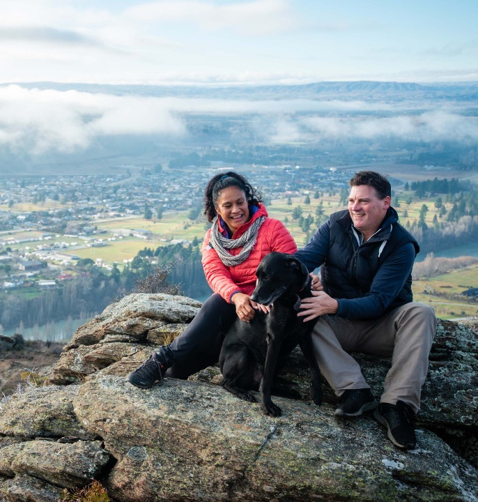 Two people sitting on a rock overlooking a town