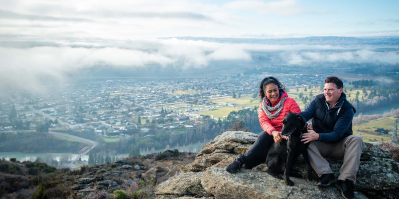Two people sitting on a rock overlooking a town