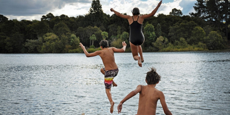 Kids jumping off a dock into a lake