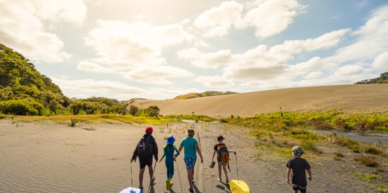 Kids walking on the sand pulling body boards