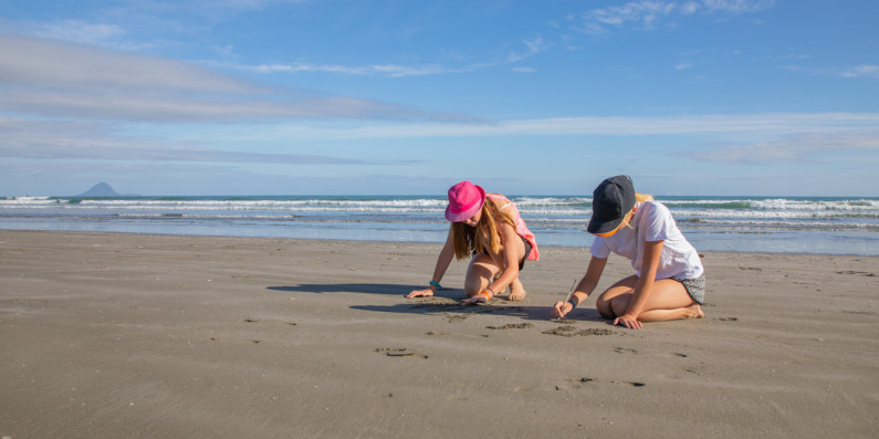 Two kids playing in the sand on a beach.