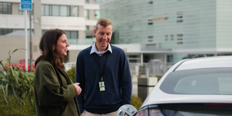 Two people talking while an electric vehicle charges.