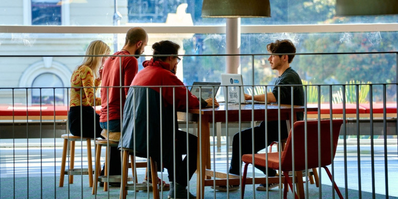 A group of people sitting at a table with their laptops for the Climathon 2021.